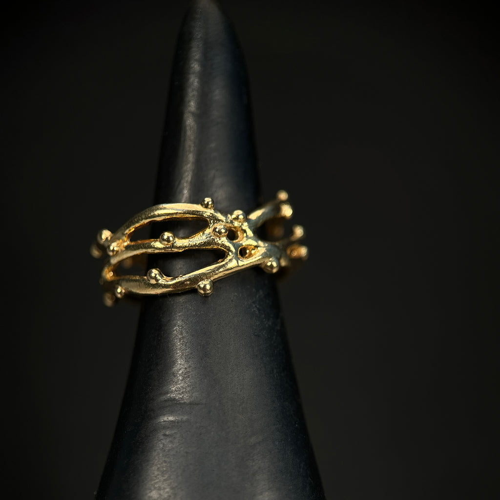 three intertwined slim branches with tiny bud-like balls scattered on the branches; shown in yellow gold